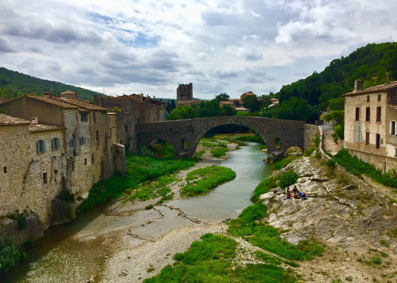 Die alte Steinbrücke von Lagrasse über den Orbieu, dahinter der Turm der Abtei